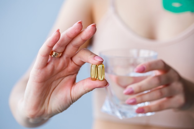 Headache, hand with pills. The woman takes medicine with a glass of water. Daily value of vitamins, effective drugs, modern pharmacy for body and mental health concept.