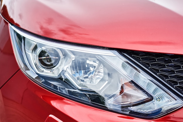 Headlight with halogen lamp on modern red car, close up