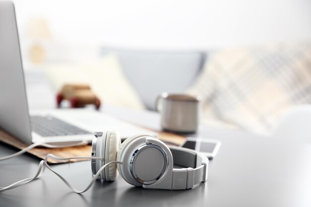 Photo headphones phone and laptop on white table against defocused background