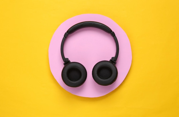 Headphones on a pink circle Yellow background Minimalism Top view