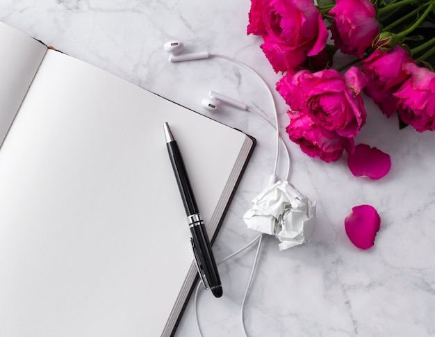 Headphones, and roses bouquet with blank notepad on white 