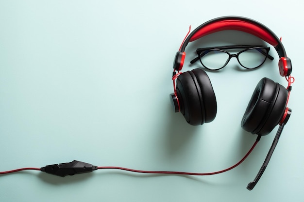 Headphones with glasses and a smartphone on a light blue background The desktop of a modern blogger with a place for text