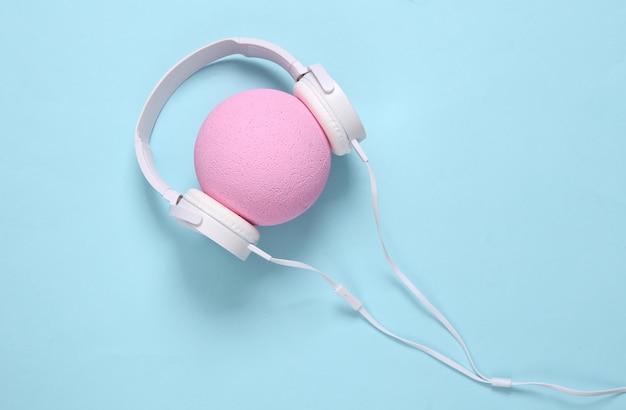 Headphones worn on pink ball on blue background Creative layout Minimalism music concept