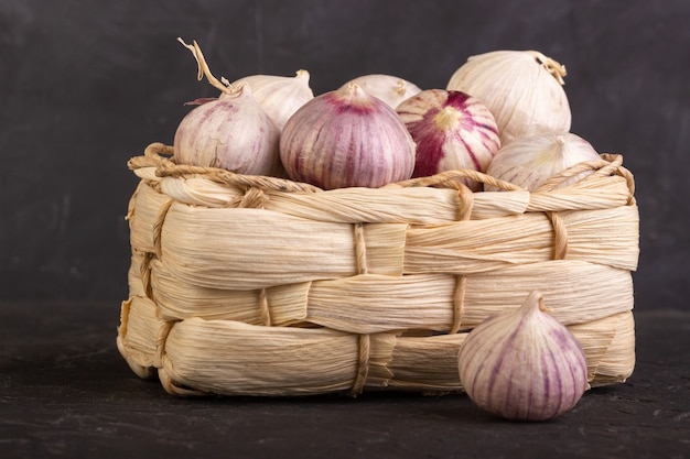 Heads of garlic in a wicker basket on a dark background