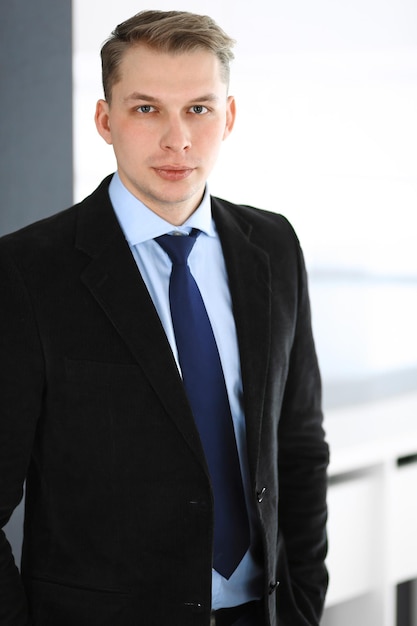 Headshot of businessman standing straight in office. Success and business workplace concept