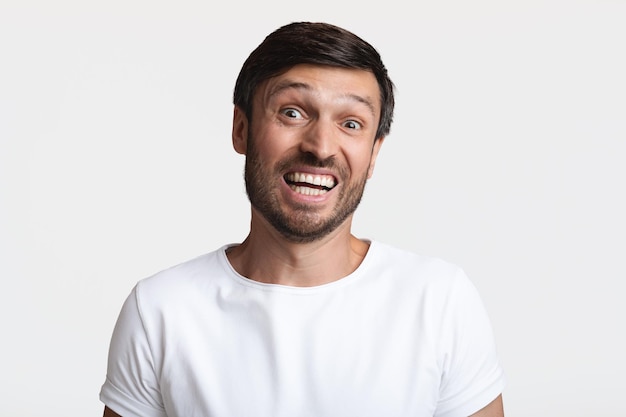 Headshot of confused bearded man shrugging shoulders over white background