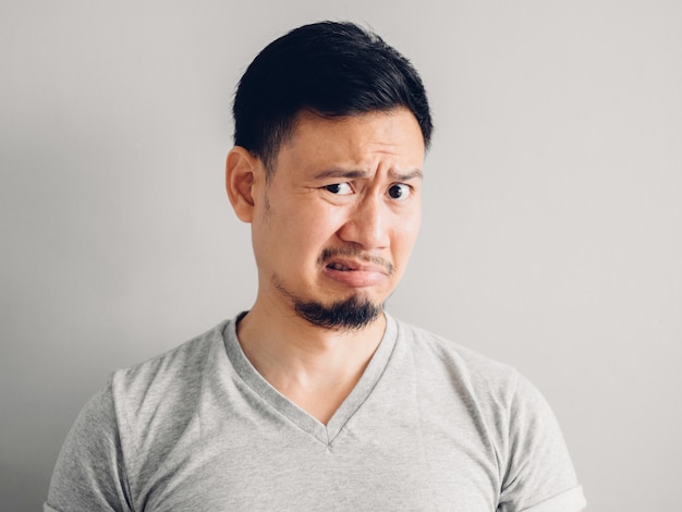 Headshot photo of Asian man with hate and disgusting face. on grey background.