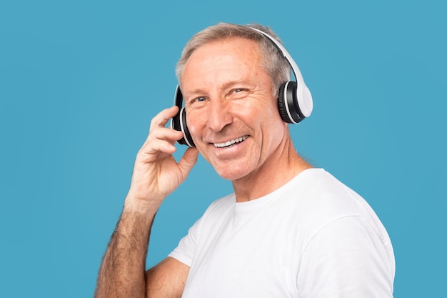 Headshot portrait of excited mature man wearing wireless headphones