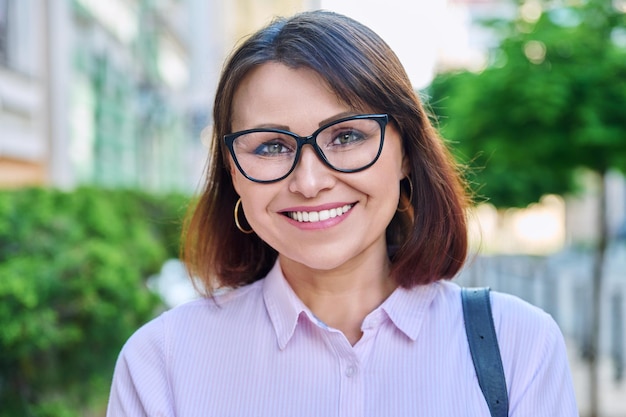 Headshot of smiling middle aged woman looking at camera outdoor