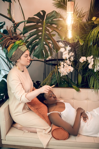 Healing. Young healer working woith a dark-skinned patient in ayurvedic salon