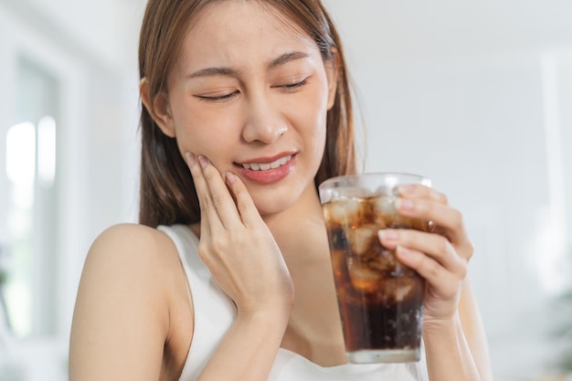 Health asian young woman touching cheek expression suffering from toothache decay or sensitivity cavity molar tooth teeth or inflammation drink cold sparkling water at homeSensitive teeth people