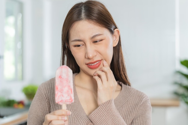 Health asian young woman touching cheek expression suffering from toothache decay or sensitivity cavity molar tooth teeth or inflammation eat cold ice cream at home Sensitive teeth people