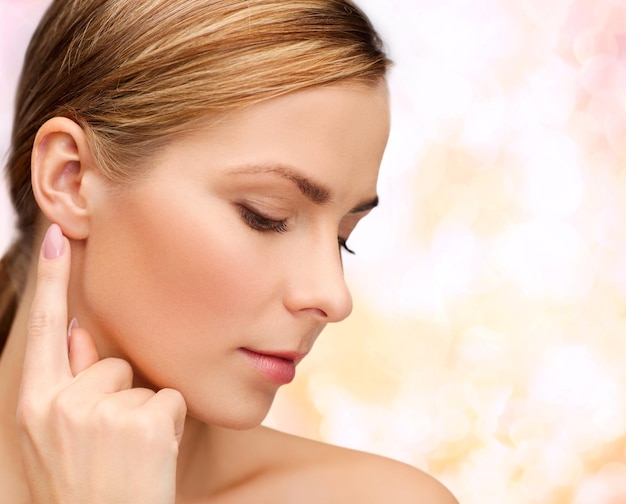 health and beauty concept - face of beautiful woman touching her ear