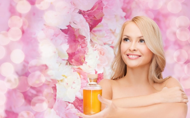 health and beauty concept - happy woman with oil bottle