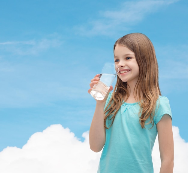 health and beauty concept - smiling little girl with glass of water