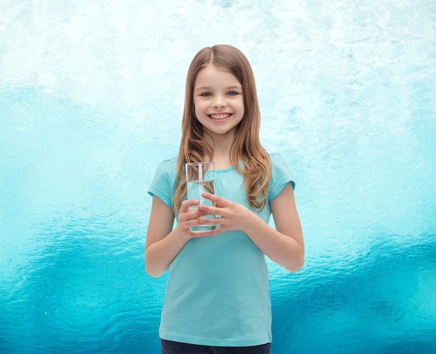 health and beauty concept - smiling little girl with glass of water