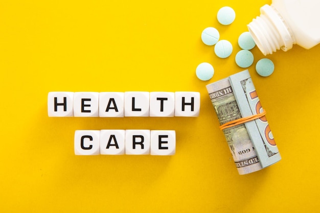 Photo health care word with money and medicine on yellow background