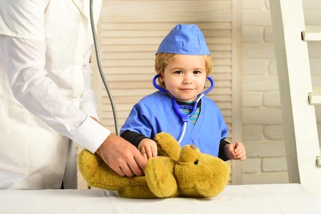 Health and childhood concept boy in medical gown holds stethoscope