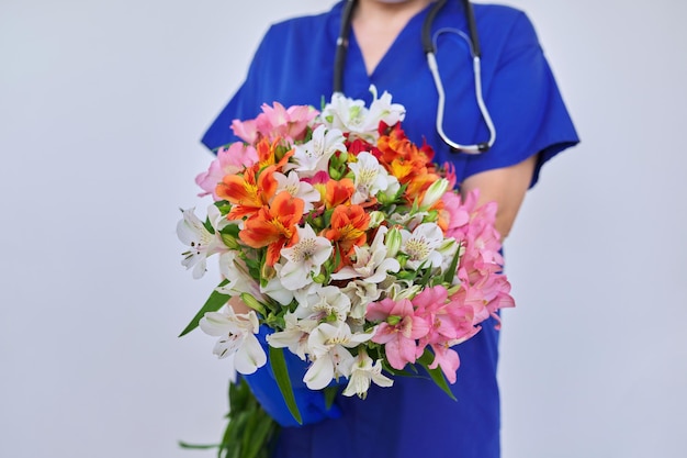 Health day closeup bouquet of flowers in the hands of doctor nurse