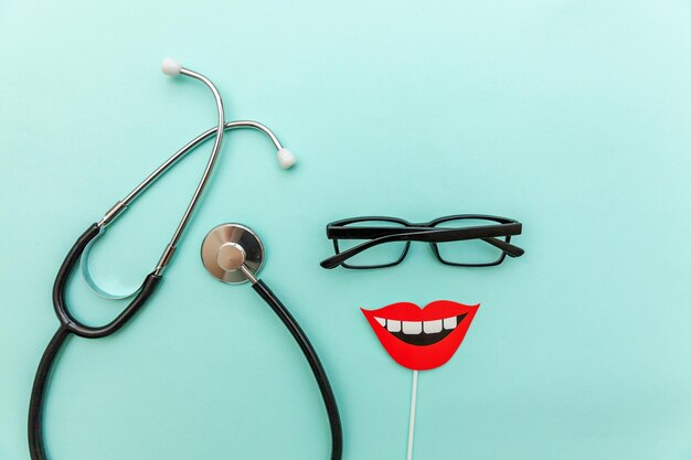 Photo health dental care concept medicine equipment stethoscope or phonendoscope glasses sign of smile teeth isolated on trendy pastel blue background