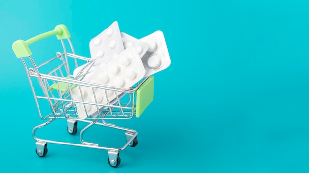 Health and medicine pills in a cart trolley on a green background with copy space