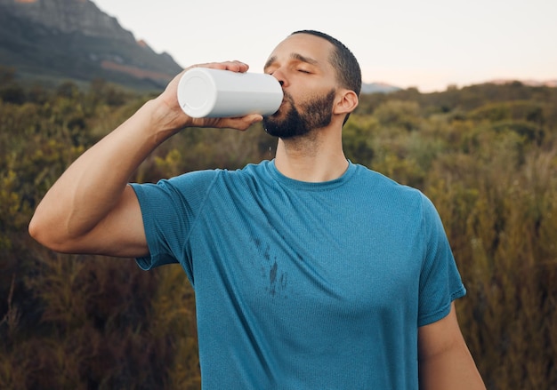 Photo health mountain and drinking water with man in nature for fitness wellness and relax after running workout exercise and sports with runner training in grass field path for challenge and peace