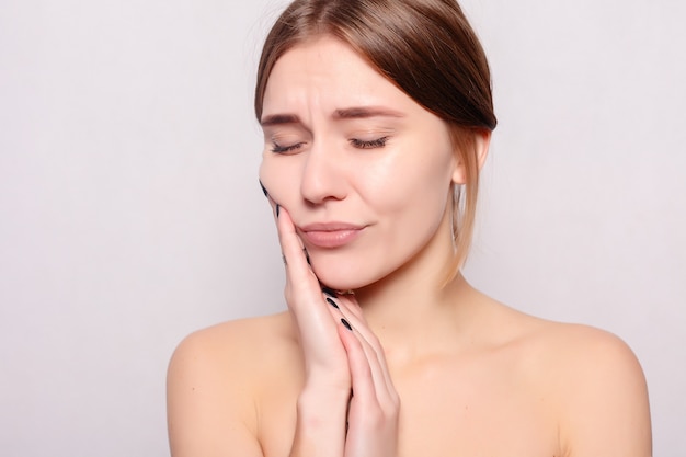 Health, people, Dental and lifestyle concept - Teeth Problem. Woman Feeling Tooth Pain. Closeup Of Beautiful Sad Girl Suffering From Strong Tooth Pain. Attractive Female Feeling Painful Toothache