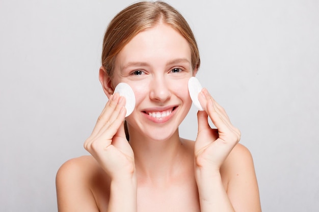 Health, people, youth and beauty concept - Woman using cotton pad. woman cleaning skin by cotton pad. Beautiful Spa Woman Smiling. Perfect Fresh Skin. Youth and Skin Care Concept