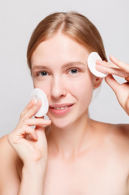 Health, people, youth and beauty concept - Woman using cotton pad. woman cleaning skin by cotton pad. Beautiful Spa Woman Smiling. Perfect Fresh Skin. Youth and Skin Care Concept