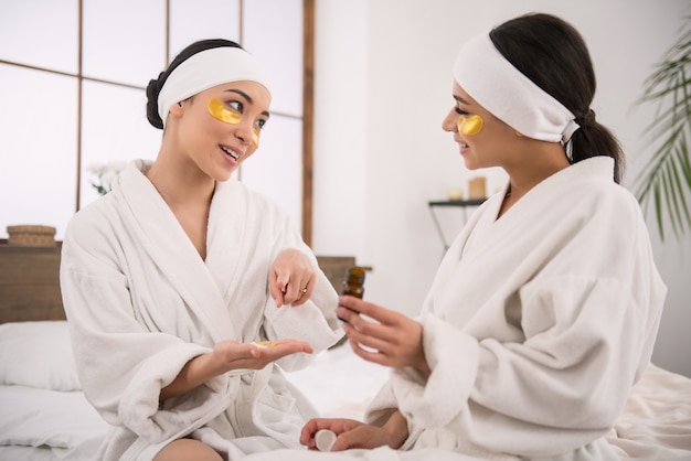 For health. Positive attractive woman pointing at the pills while recommending them to her friend