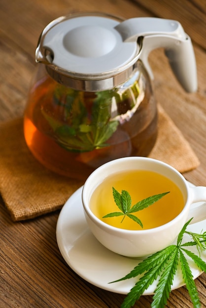 Health tea with hemp leaf plant THC CBD herbs food and medical concept Cannabis tea herbal on tea cup and jug with cannabis leaf marijuana leaves herb on wooden