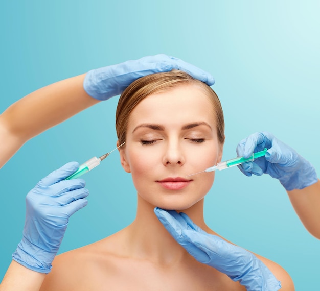 healthcare, beauty and medicine concept - beautiful woman face with closed eyes and beautician hands with syringe