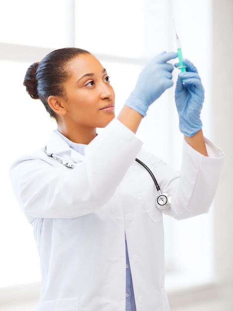 healthcare and medical concept - african doctor holding syringe with injection