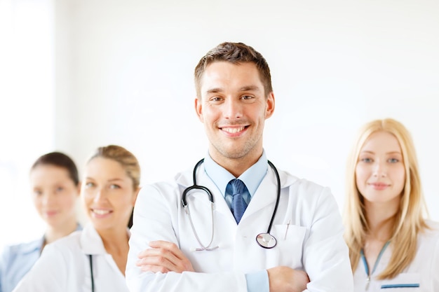 healthcare and medicine concept - attractive male doctor in front of medical group in hospital