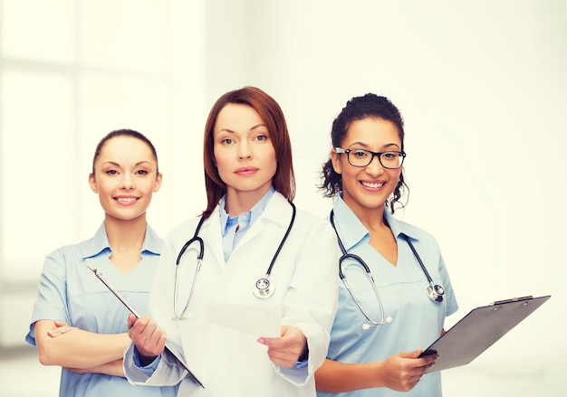 healthcare and medicine concept - calm female doctor and nurses with clipboard and stethoscope giving prescription