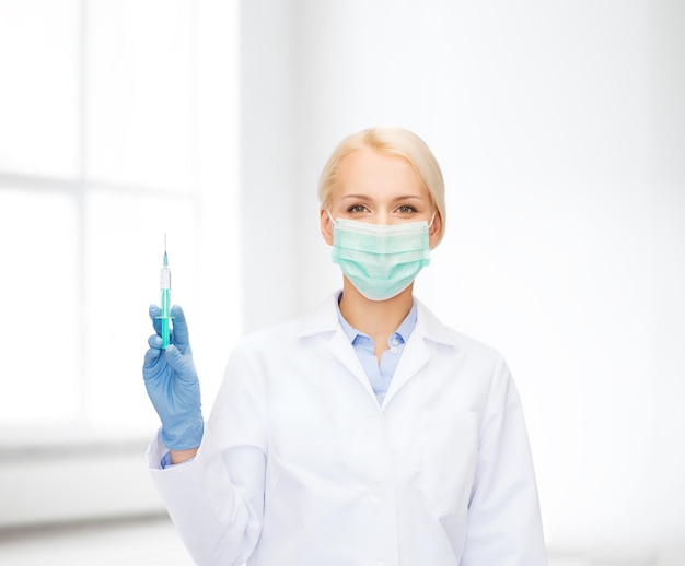 healthcare and medicine concept - female doctor in mask holding syringe with injection