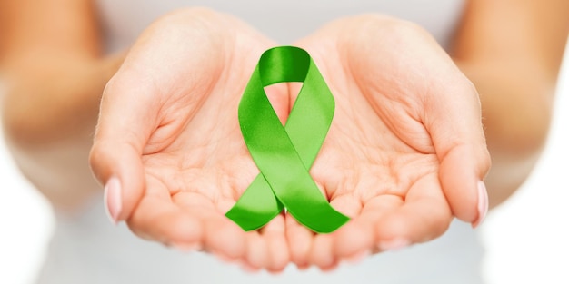 healthcare and medicine concept - female hands holding green organ transplant awareness ribbon