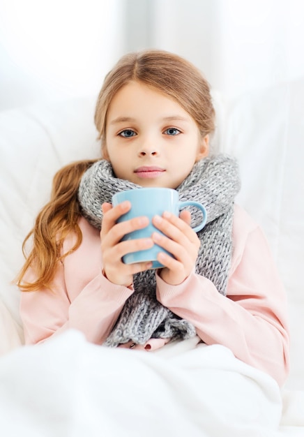 healthcare and medicine concept - ill girl child with cup of hot tea