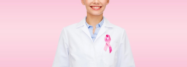 healthcare and medicine concept - smiling female doctor with pink cancer awareness ribbon over pink background