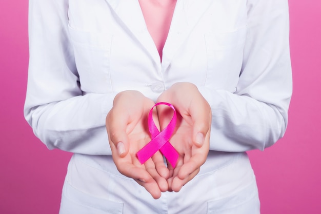 Healthcare and medicine concept - womans hands holding pink breast cancer awareness ribbon.