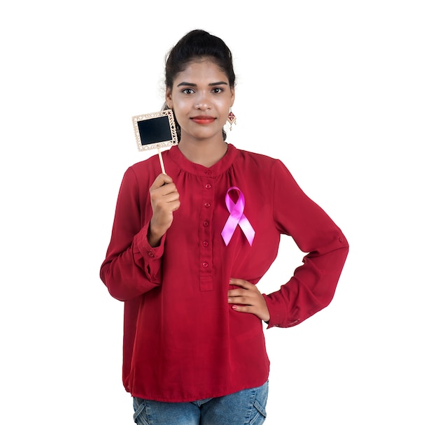 Healthcare and medicine concept - young woman hands holding pink breast cancer awareness ribbon and small black board