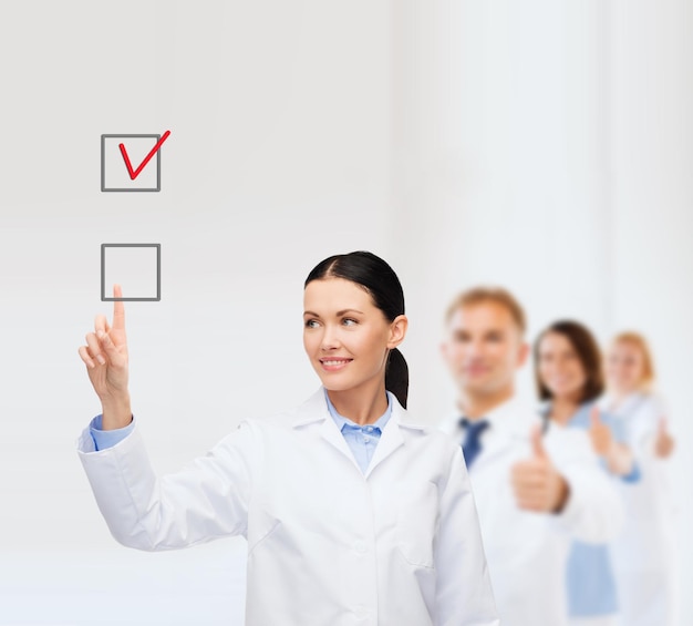 healthcare, medicine and technology concept - smiling female doctor pointing to checkbox