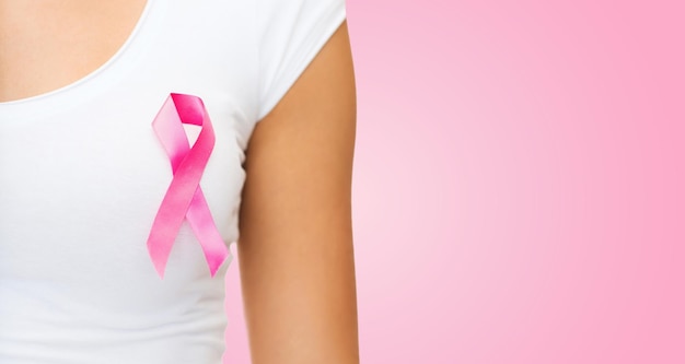 healthcare, people, charity and medicine concept - close up of woman in t-shirt with breast cancer awareness ribbon over pink background