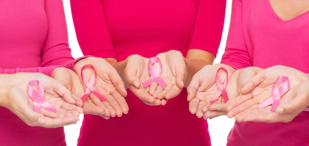 healthcare, people and medicine concept - close up of women in blank shirts with pink breast cancer awareness ribbons over white background