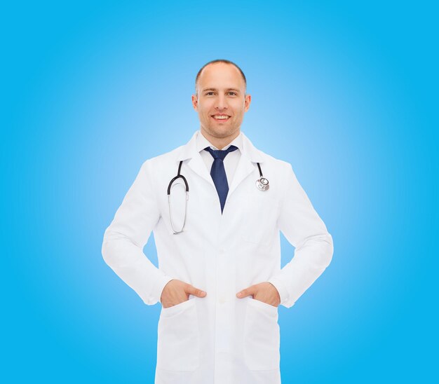 healthcare, profession and medicine concept - smiling male doctor with stethoscope in white coat over blue background