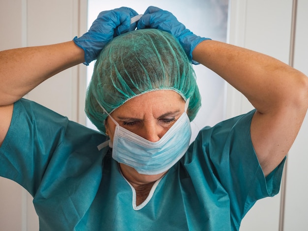 Healthcare professional woman with protection against covid 19 putting her mask