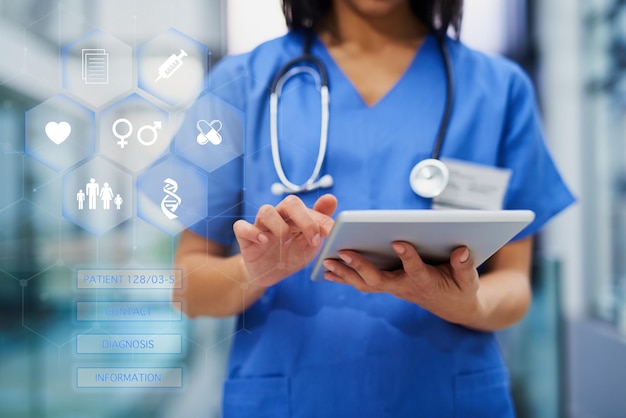 Healthcare solutions at the touch of a button Cropped shot of an unrecognizable female nurse using a tablet while standing in the hospital