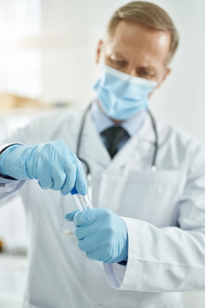 Healthcare worker in medical mask holding test tube