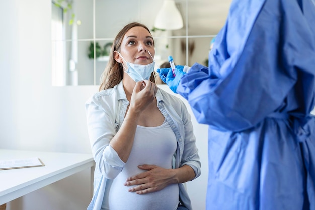 Healthcare worker with protective equipment performs coronavirus swab on pregnant woman.Nose swab for Covid-19.