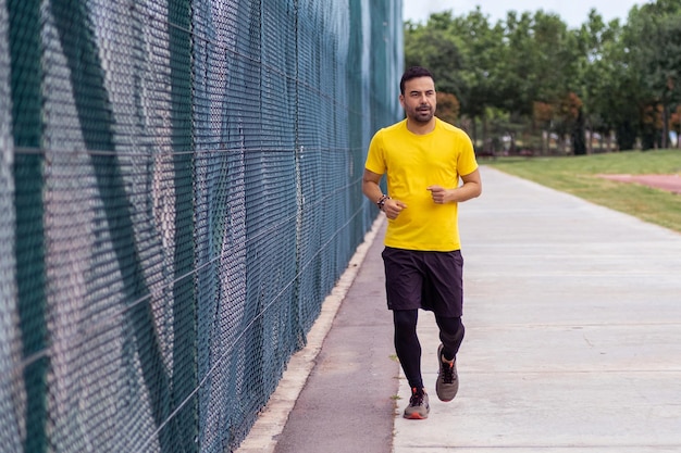 Healthconscious man runs along sports ground in an urban park fitness and body development